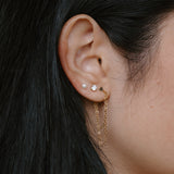 Close-up of an ear with gold earrings and dark hair