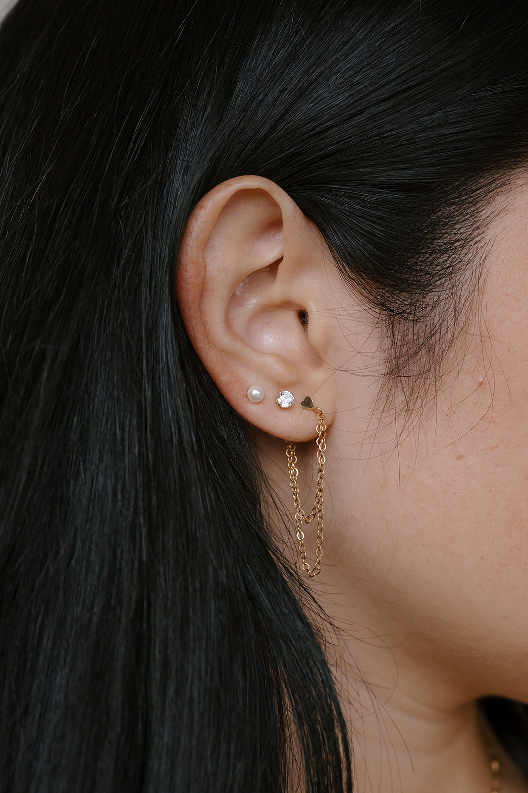 Close-up of an ear with gold earrings and dark hair