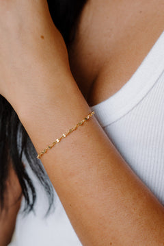 Close-up of a person wearing a gold bracelet on a blurred background
