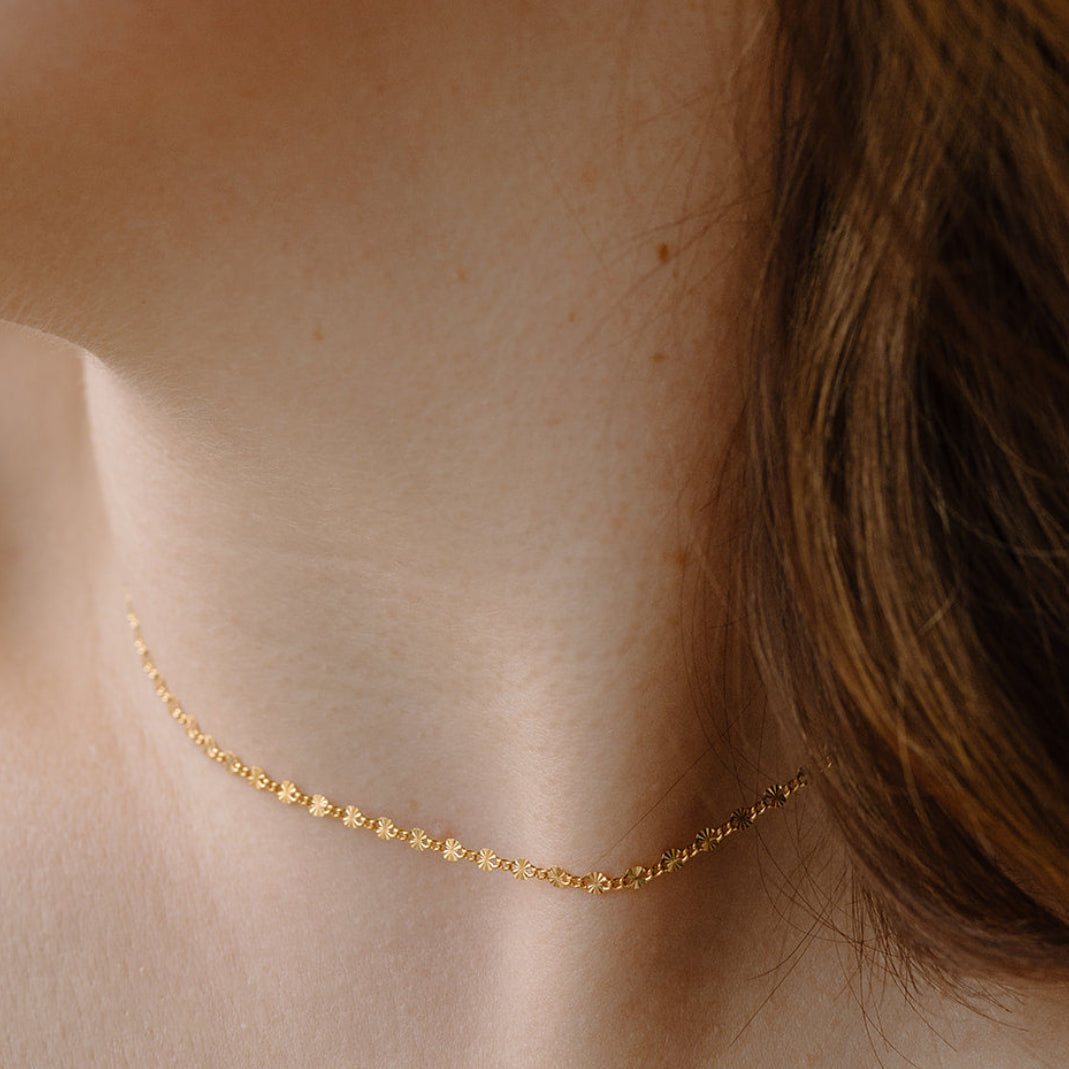 Close-up of a person wearing a delicate gold necklace.
