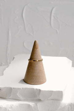 Minimal dot stacking ring in 14k gold filled and sterling silver, displayed on neutral ring cone with textured white backdrop