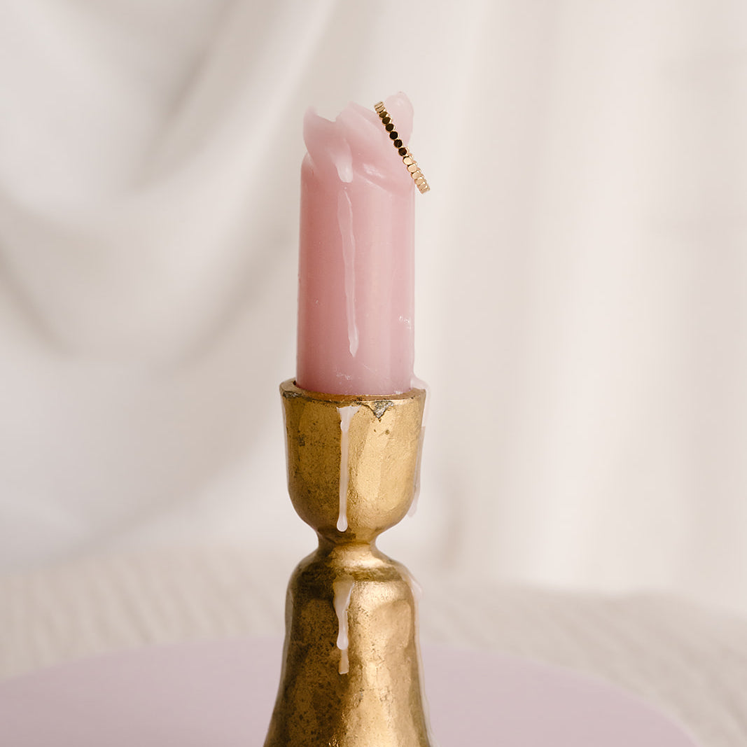 Dot stacking ring available in 14k gold filled and sterling silver, styled on melted pink candle in vintage gold candlestick holder with neutral backdrop