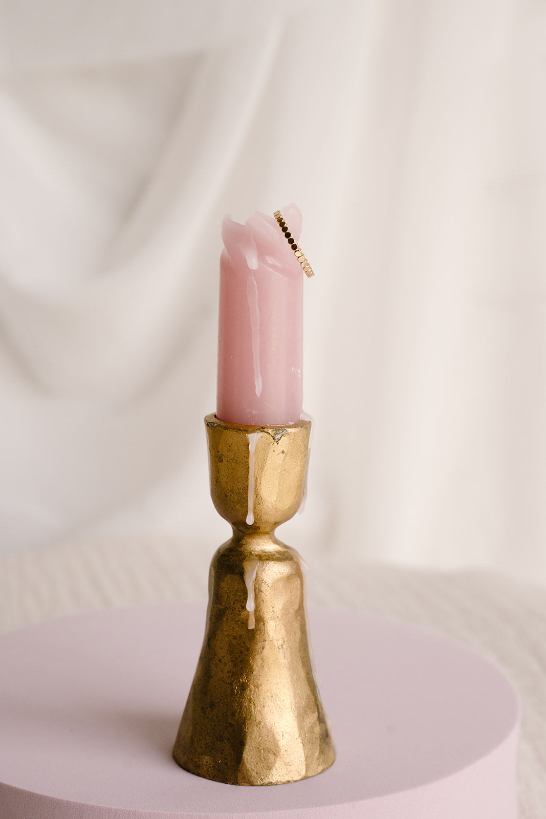 Dot stacking ring available in 14k gold filled and sterling silver, styled on melted pink candle in vintage gold candlestick holder with neutral backdrop
