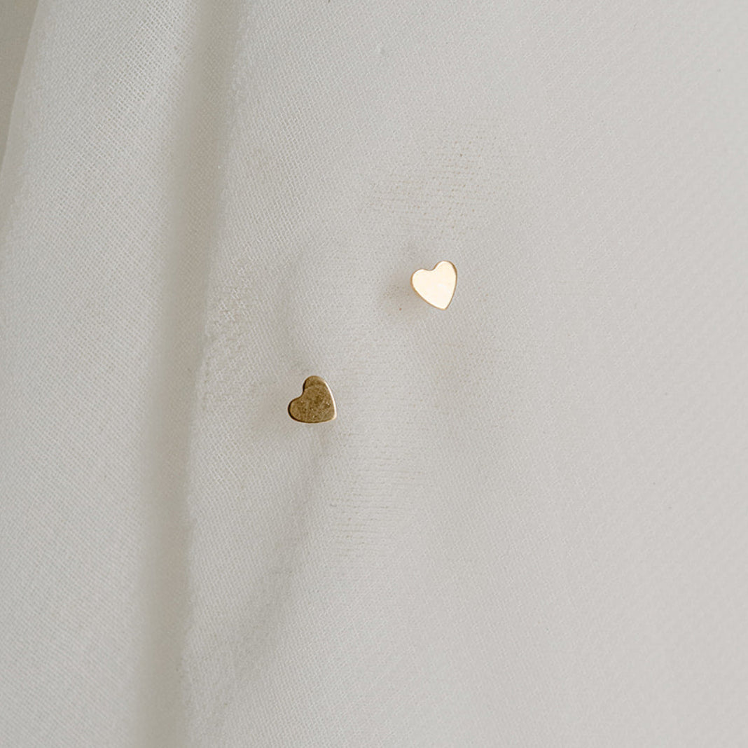 Two heart-shaped earrings on a light fabric background